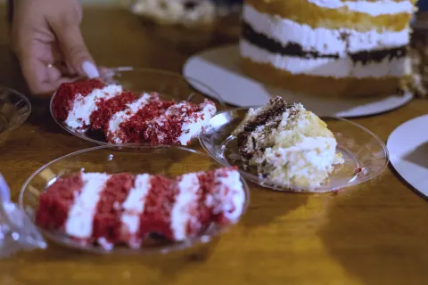 A hand reaches for a slice of cake on a party table
