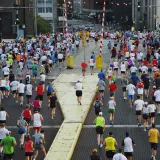 Hundreds of runners at the start of a city marathon, seen from behind on a wide street