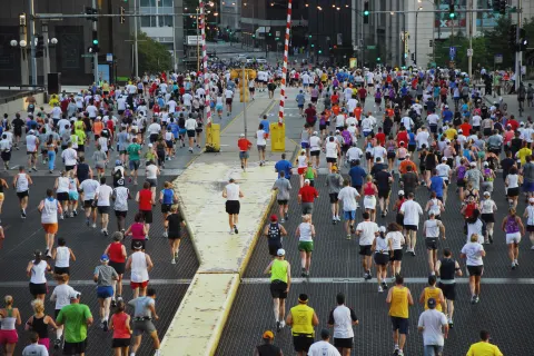 Hundreds of runners at the start of a city marathon, seen from behind on a wide street