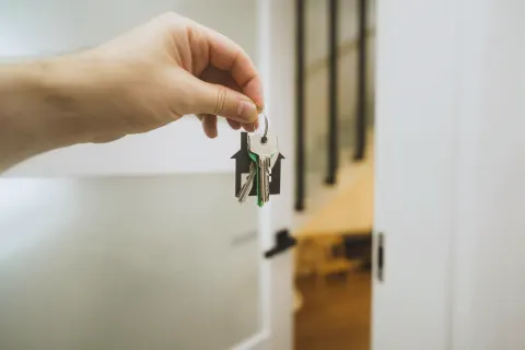 A hand holding a bunch of keys by an open white door