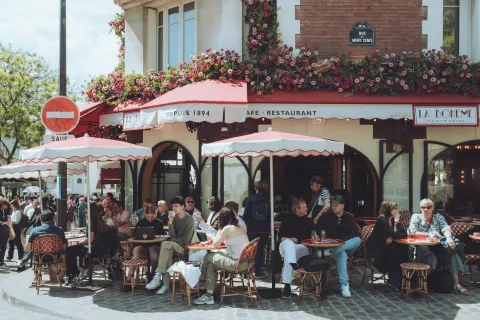 A busy café terrace in Paris on a sunny day, every table taken