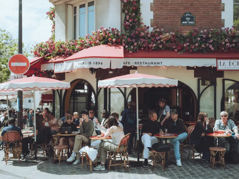 A busy café terrace in Paris on a sunny day, every table taken