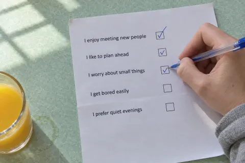 A hand ticking boxes on a printed quiz sheet on a mint green kitchen table